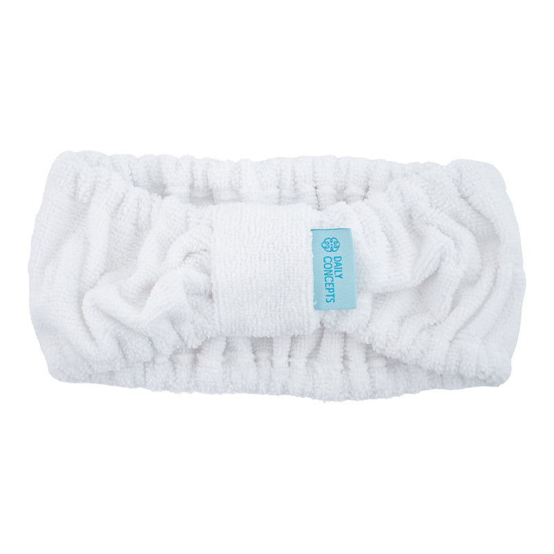 A white plush terry cloth headband with a central textured band and a small light blue fabric tag that reads 'DAILY CONCEPTS'.